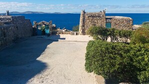 A coastal fortification with stone walls and a gate, overlooking the sea. - Cavo Nano (Mykonos)