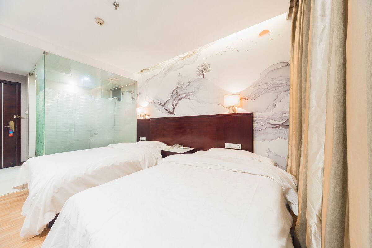 A hotel room with two beds, a large mirror, and a wall mural.