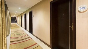 Un pasillo de hotel con piso alfombrado, puertas de madera y un letrero que indica la oficina.