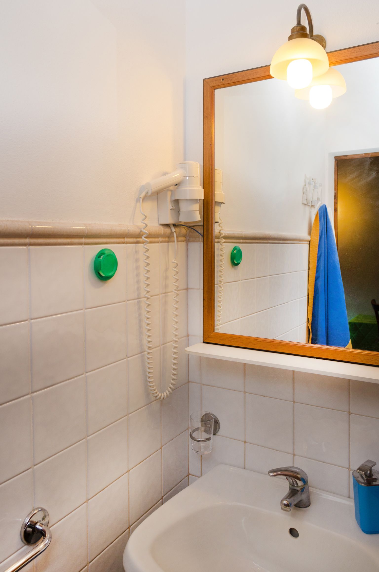 A bathroom with a white sink, a mirror with a wooden frame, and a telephone mounted on the wall.