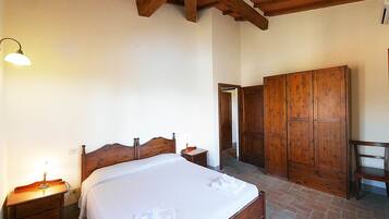 Un dormitorio con cama de madera, una mesita de noche con lámpara, un armario y una silla.