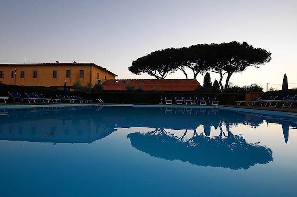 A swimming pool with clear water reflecting trees and buildings.