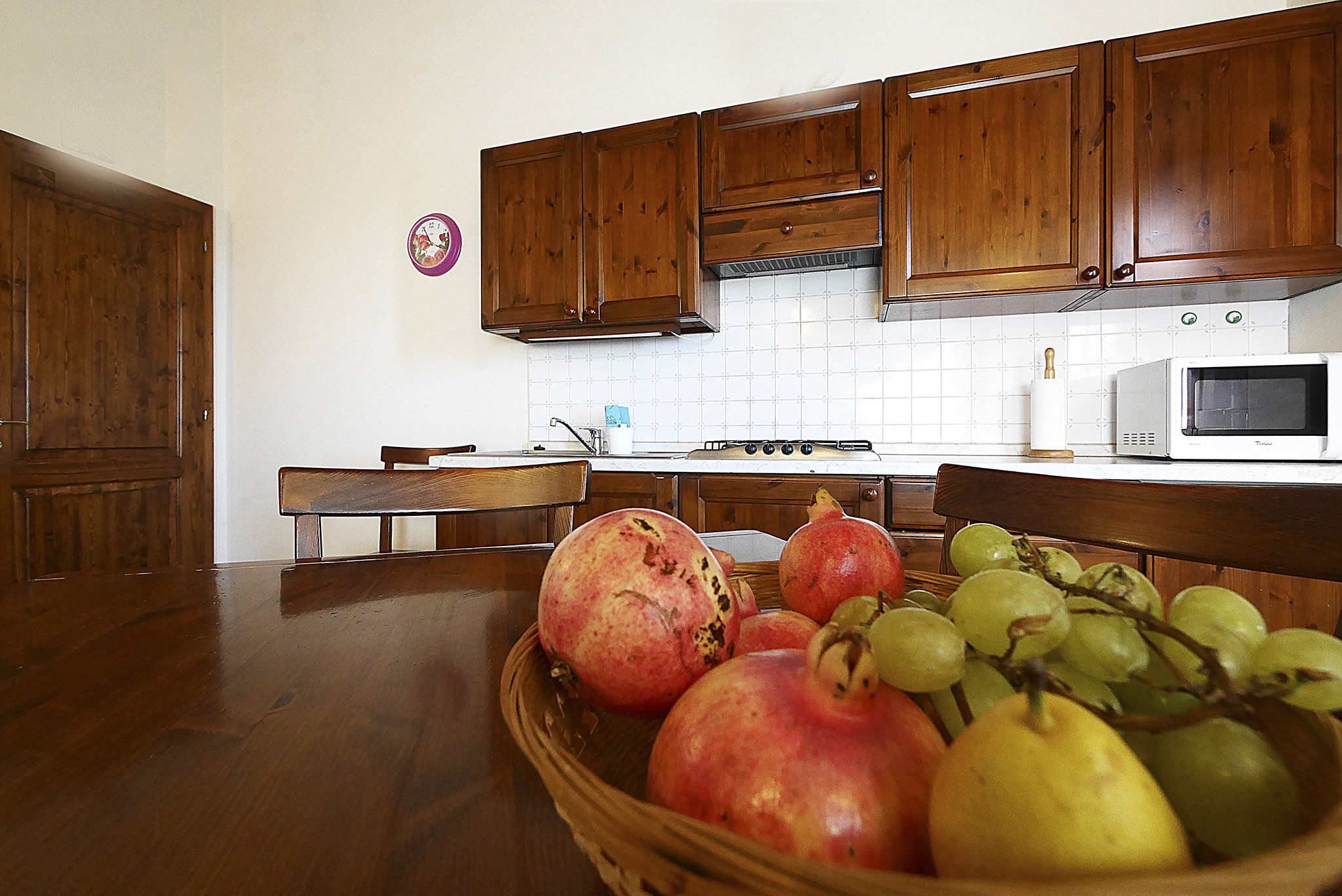 A kitchen with wooden cabinets, a microwave, and a fruit bowl on the counter.