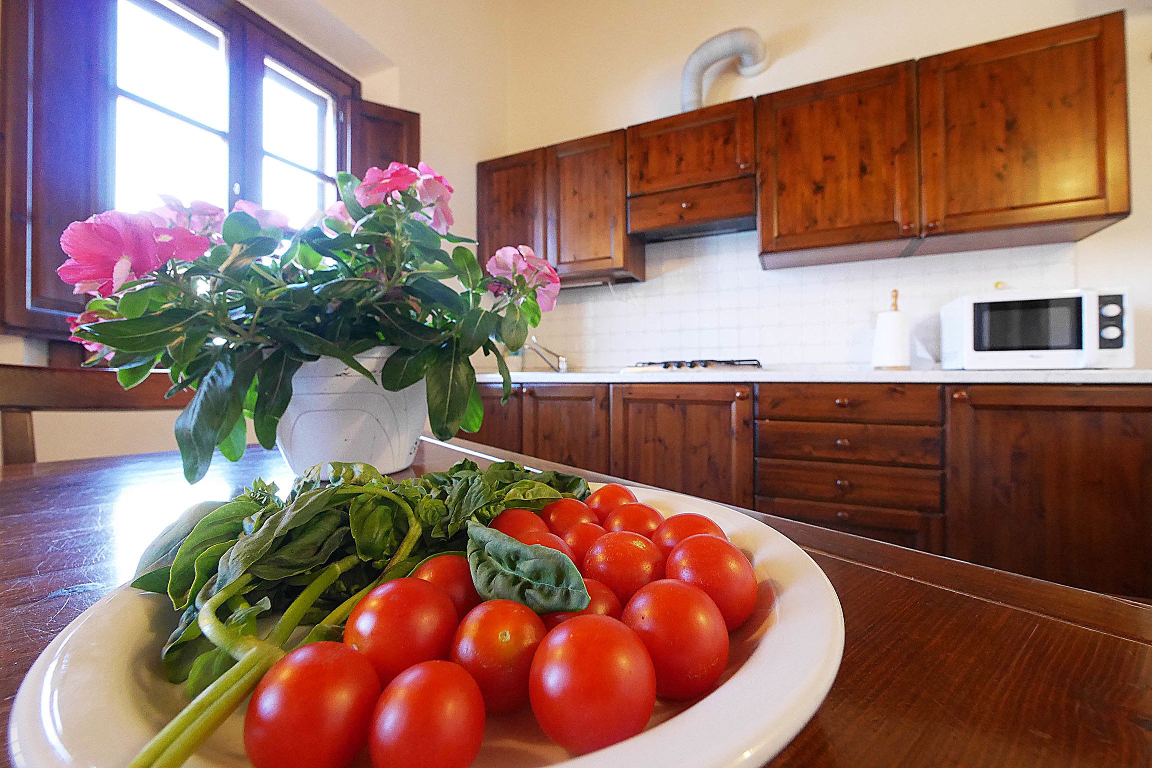Eine Küche mit Holzausstattung, einer weißen Mikrowelle und einem Teller mit Tomaten und Basilikum.
