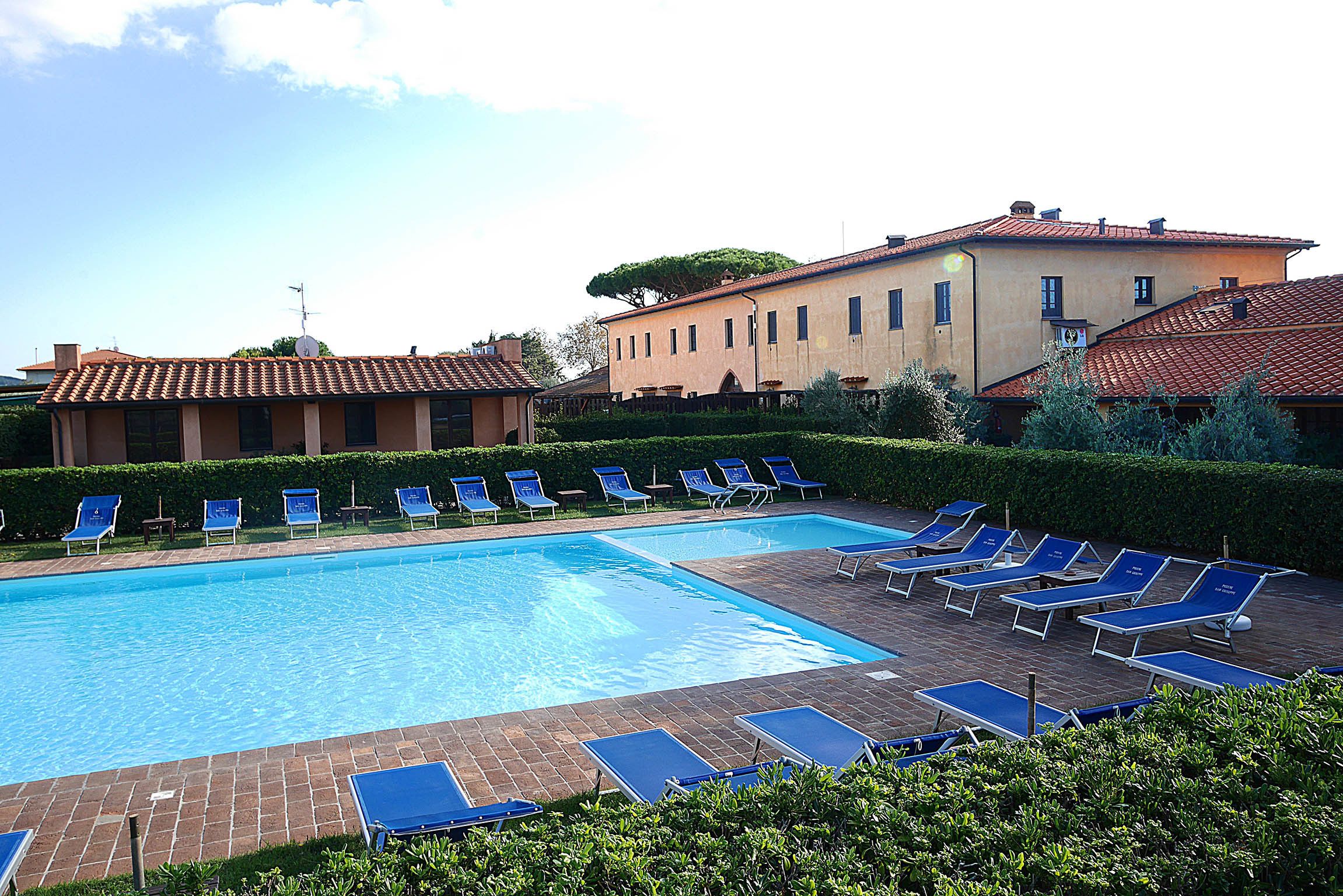 A swimming pool with lounge chairs and a building in the background.