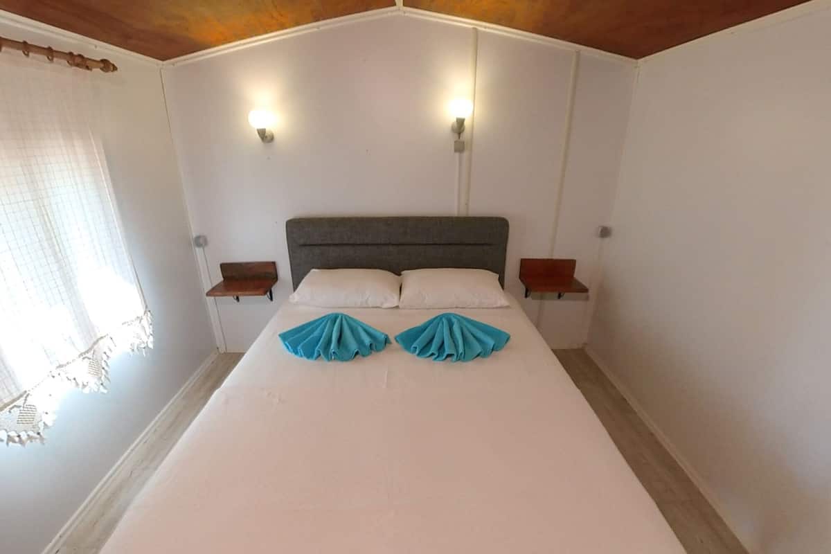 A large bed with a grey headboard, two bedside tables, and two wall-mounted lights.