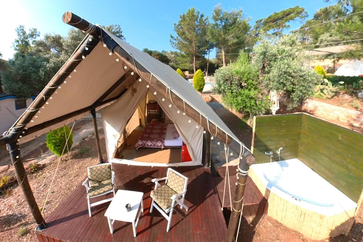 A tent with a wooden deck, a hot tub, and outdoor seating.