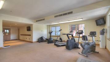 Ein großzügiger Fitnessraum mit mehreren Laufbändern, Ergometer und einem Crosstrainer.
