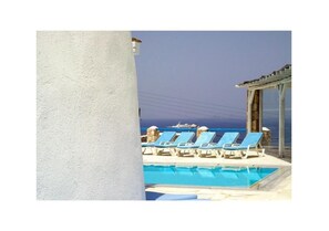 A pool area with lounge chairs and a view of the sea. - Villa Adonis (Mykonos)