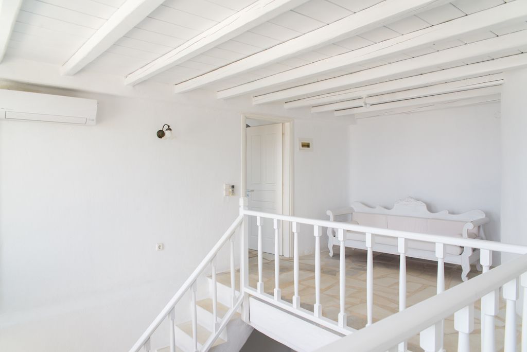 A white interior with a staircase, a door, and a bench.