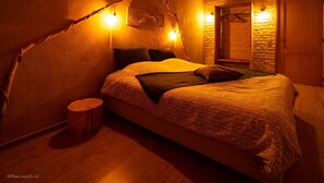 Un dormitorio acogedor con una cama grande, cabecera de madera y una pared de piedra rústica.