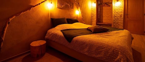 Un dormitorio acogedor con una cama grande, cabecera de madera y una pared de piedra rústica.