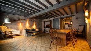 Un interior acogedor y rústico con vigas de madera a la vista, una chimenea de piedra, un comedor con sillas de madera y un sofá.