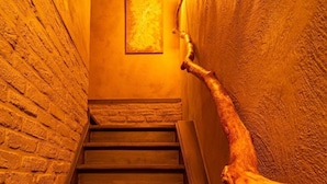 Una escalera de madera con barandilla a la derecha, que lleva a una habitación con un cuadro en la pared.