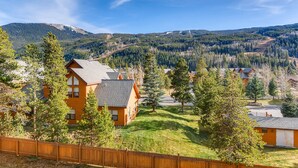A wooden cabin with a sloped roof, surrounded by a wooden fence, set in a forested area with mountains in the background. - Gateway 5039 (Keystone)
