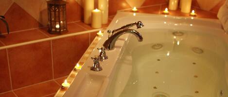 Eine Badewanne mit mehreren Kerzen und einer Laterne, umgeben von gefliesten Wänden.