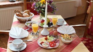 Una mesa de desayuno con diferentes alimentos, una vela y un florero con flores.