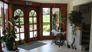 Una habitación con puerta de madera, una mesa pequeña con mantel de encaje, una silla, felpudo y una alfombra decorativa.
