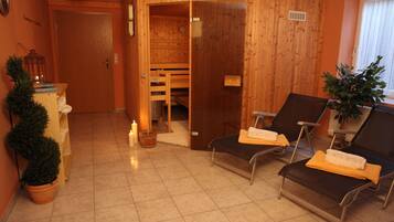 Relax in a serene sauna room with two reclining chairs and a small table.