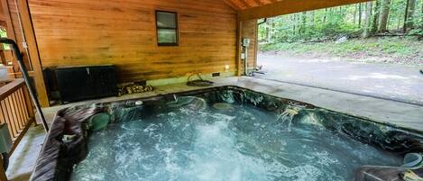A hot tub in a wooden cabin with a view of a forest.