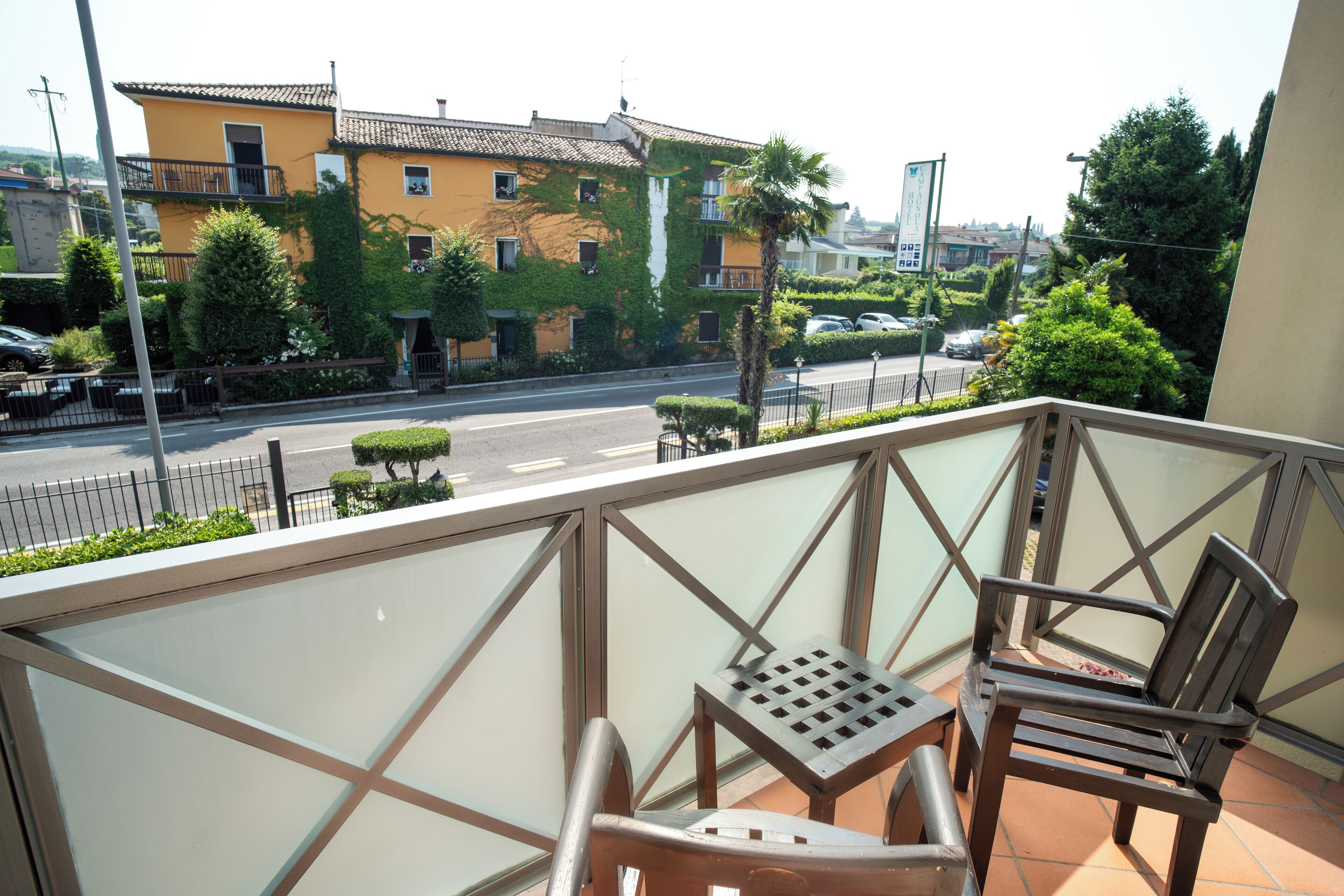 A balcony with a view of a street, a chair, and a table.