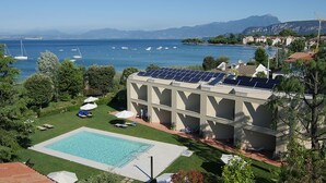 Um hotel com piscina, painéis solares e vista para o mar e montanhas.