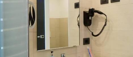 A bathroom with a white sink, a mirror, a hairdryer, and a towel rack.