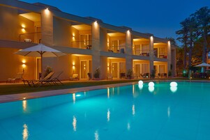 Un hotel de varios pisos con piscina, mobiliario exterior y balcones.