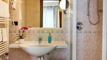 Un baño con lavabo, espejo, toallero y ducha.