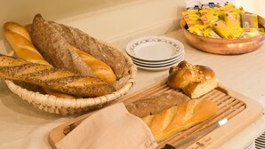 Uma bancada de cozinha com diversos pães, doces e acompanhamentos.