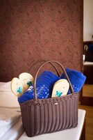 Una cesta de mimbre con toallas azules y artículos de baño sobre una cama.
