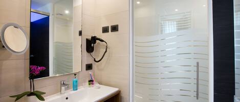 A modern bathroom with a white sink, a large mirror, and a glass-enclosed shower area.