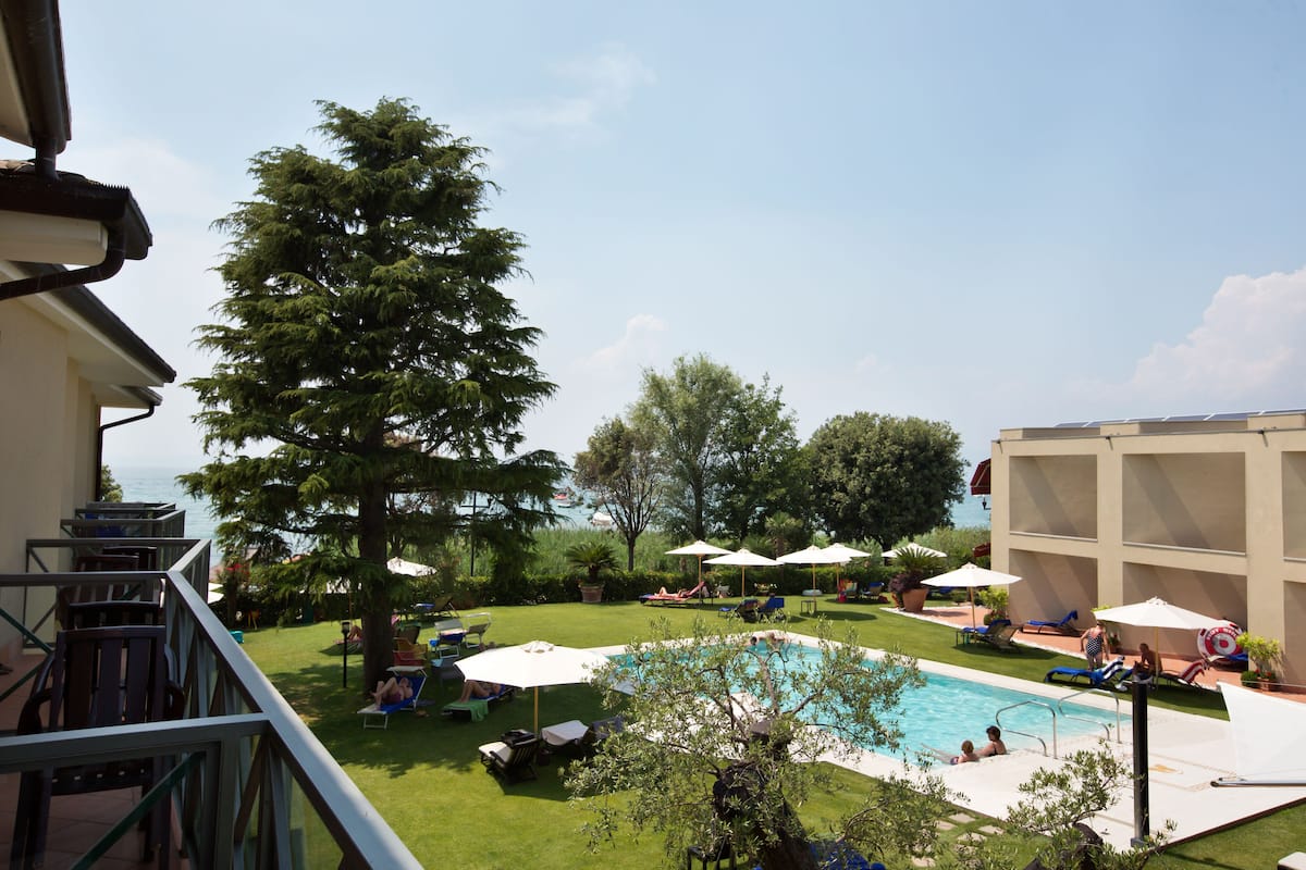 A pool area with lounge chairs, umbrellas, and a view of the sea.