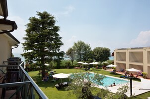 Zona de piscina con sillones de descanso, sombrillas y vista al mar.