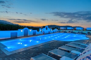 Une piscine avec des chaises longues et une vue sur le coucher de soleil.