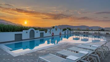 Ein Swimmingpool mit Liegestühlen und Blick auf den Sonnenuntergang.