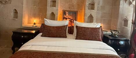 Un dormitorio con una cama grande, una chimenea y paredes de piedra con arcos.