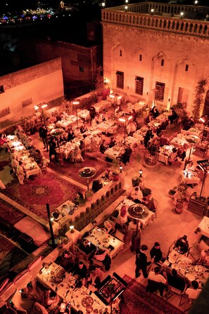 An outdoor dining area with multiple tables and chairs, surrounded by stone walls and potted plants. - Maridin Hotel - Special Class (Mardin)