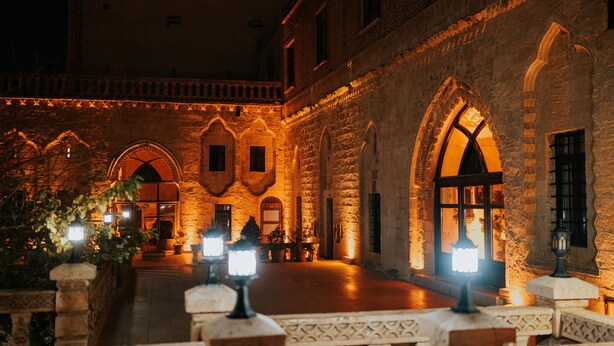 Um edifício de pedra com arcadas e janelas, iluminado por uma luz quente.