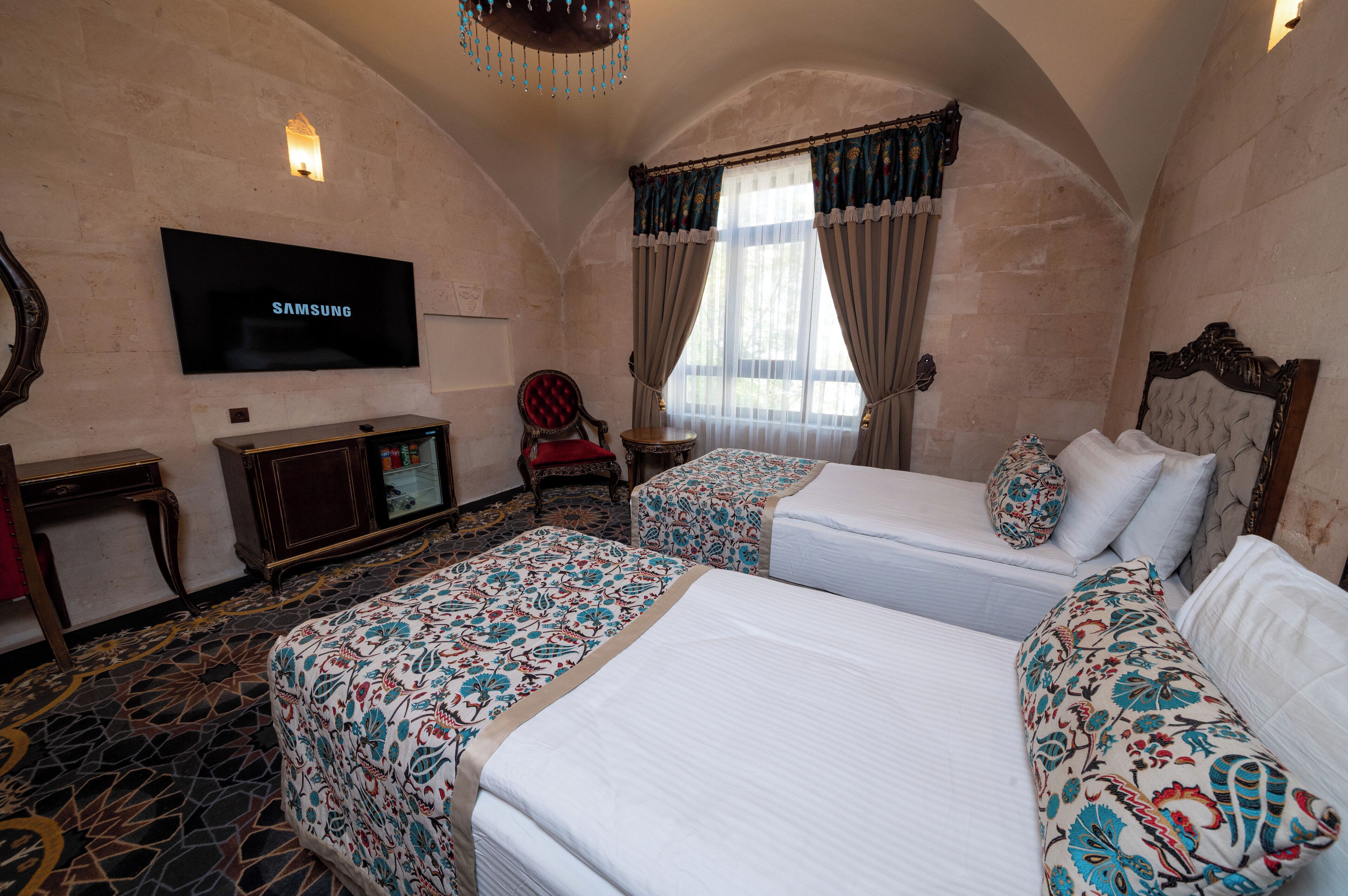 A hotel room with two beds, a TV, a desk, and a chair.