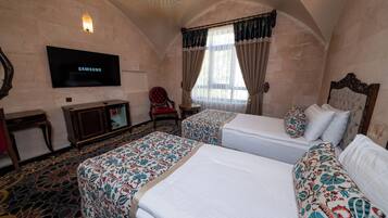 A hotel room with two beds, a TV, a desk, and a chair.