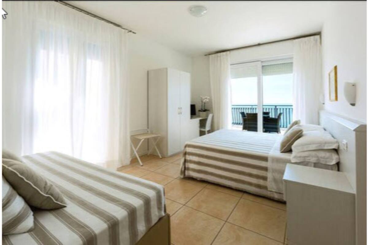 A hotel room with a bed, a desk, and a balcony.