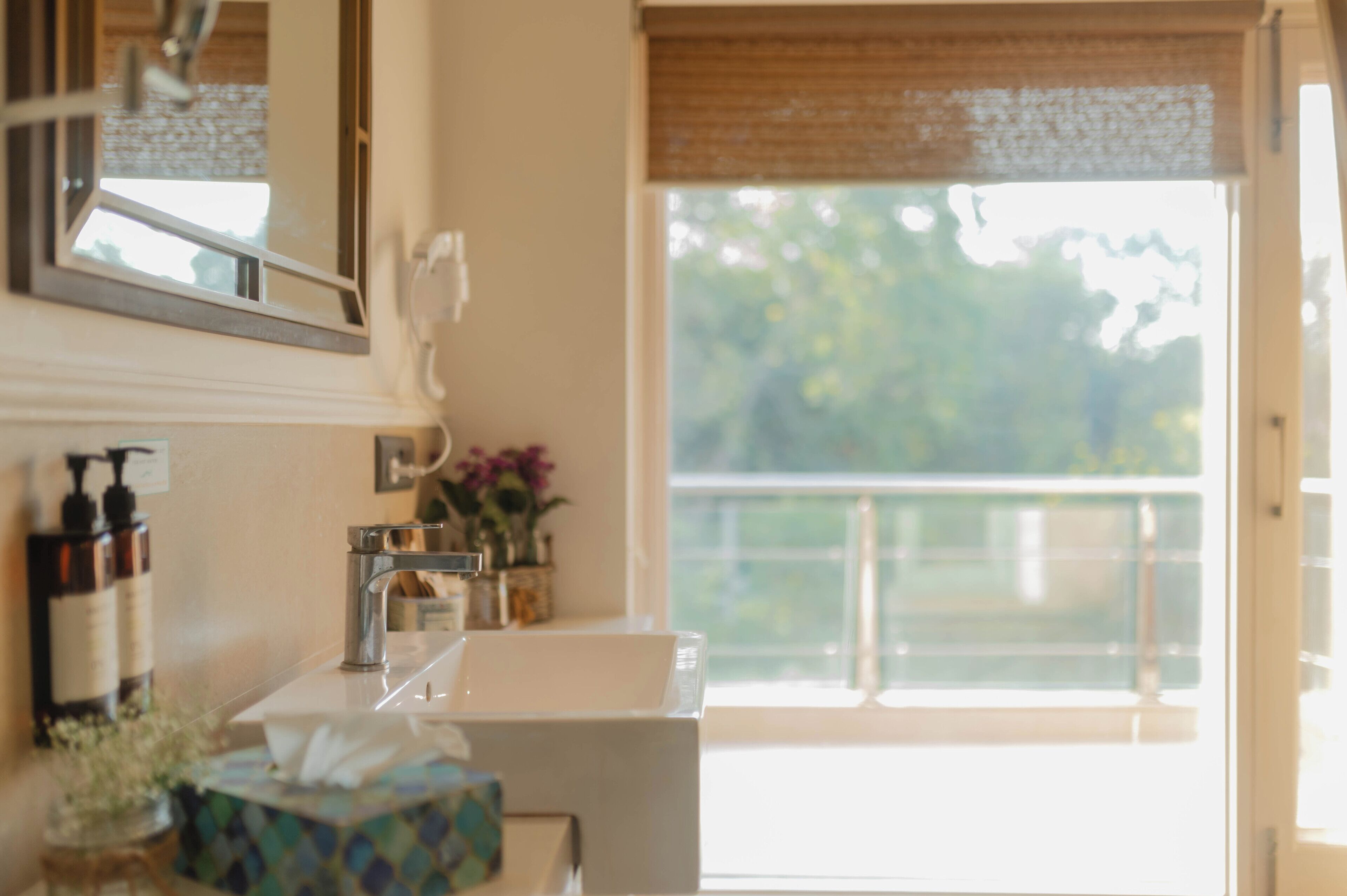 A bathroom with a sink, mirror, and window overlooking a balcony.