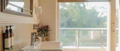 A bathroom with a sink, mirror, and window overlooking a balcony.