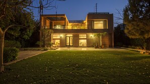 A modern two-story house with a well-maintained lawn and large windows. - Karma Chalets (Gurugram)