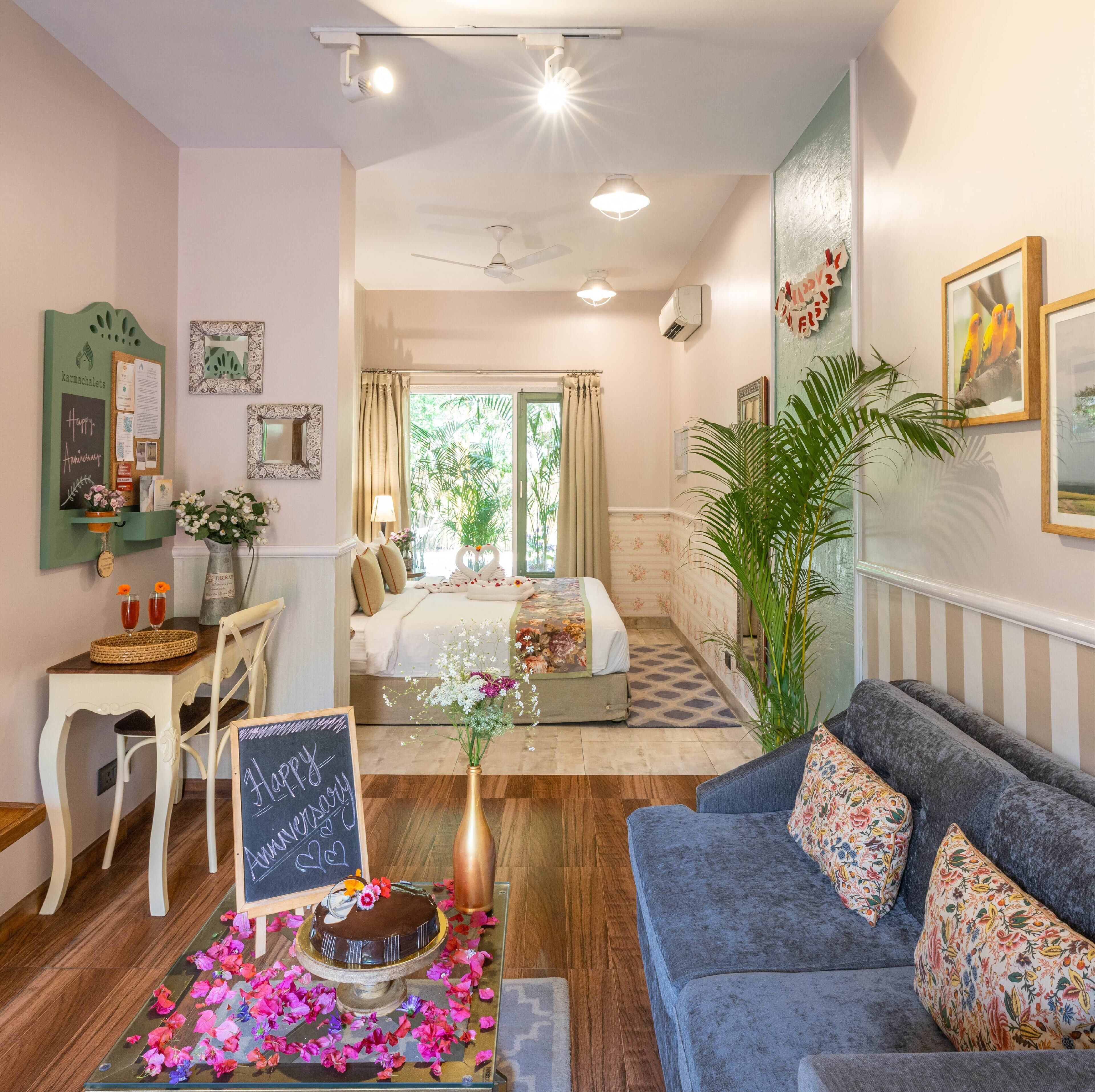 A cozy room with a bed, a sofa, a dining area with a table and chairs, and a large window with curtains.