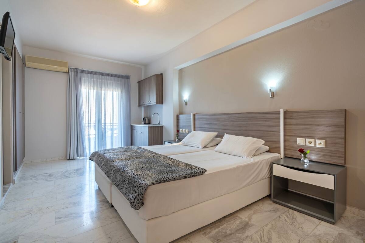 A modern hotel room with a large bed, bedside tables, a wardrobe, and a bathroom with a shower and toilet.