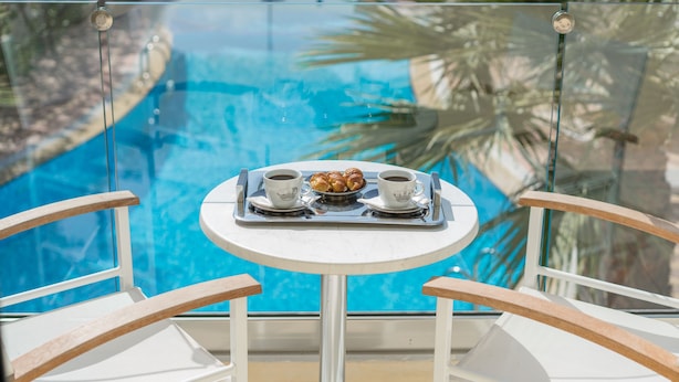 Ein von Glas umgebener Pool mit Tisch und Stühlen im Vordergrund.