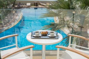 A glass-enclosed pool with a table and chairs in the foreground. - Apollo Hotel II (Apokoronas)