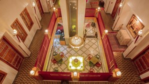 A grand lobby with a central chandelier, ornate red railings, and patterned floor tiles. - Palais Zahia (Tangier)
